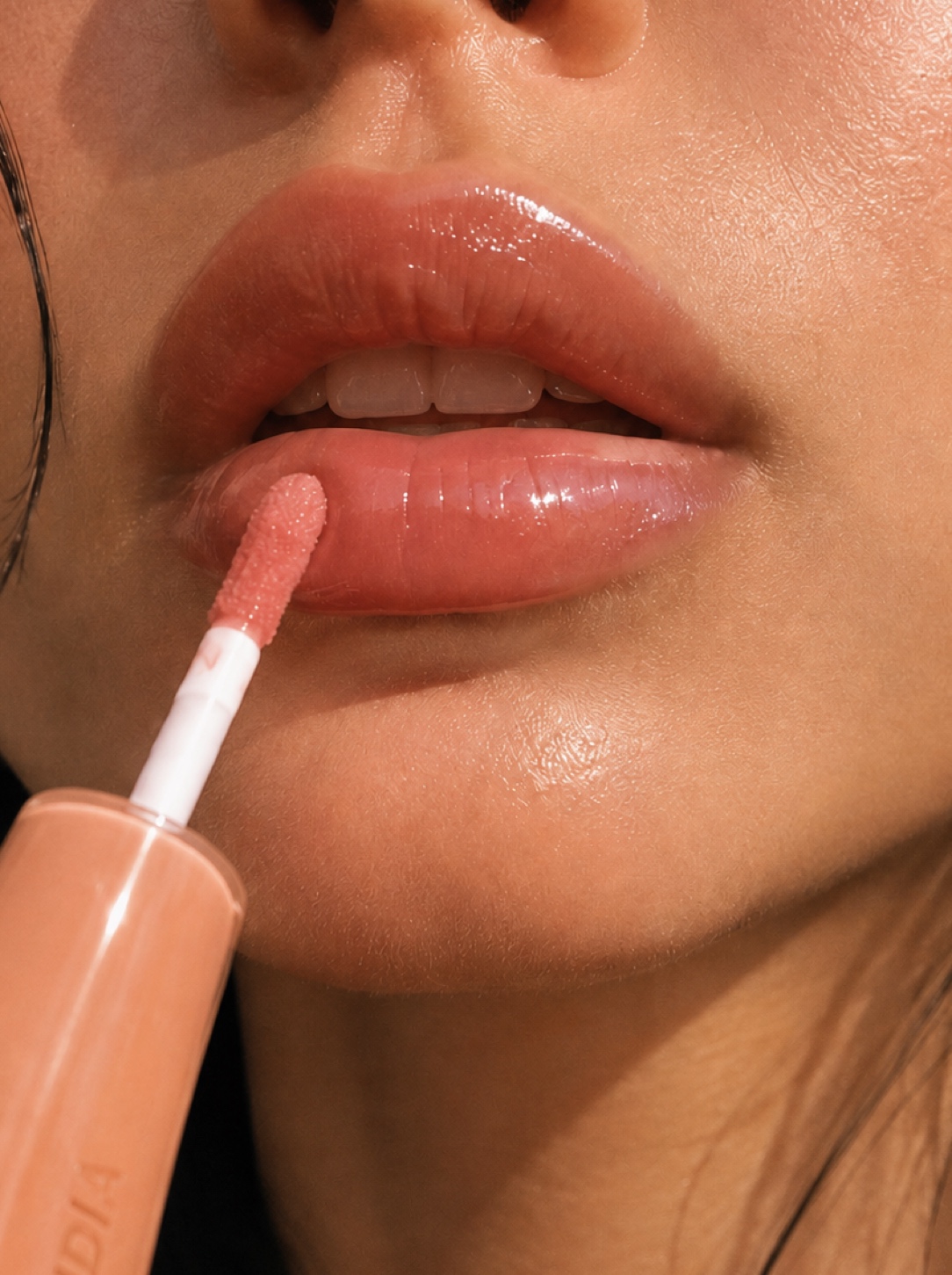 Tight close-up of glossy lips in a warm orange shade