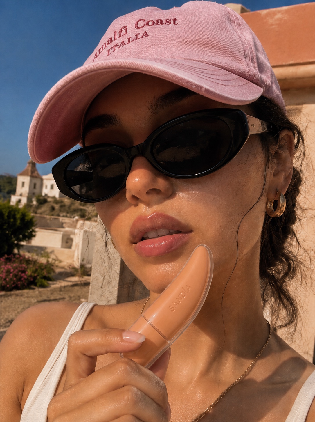 Woman in a pink cap holding SANDÍA gloss